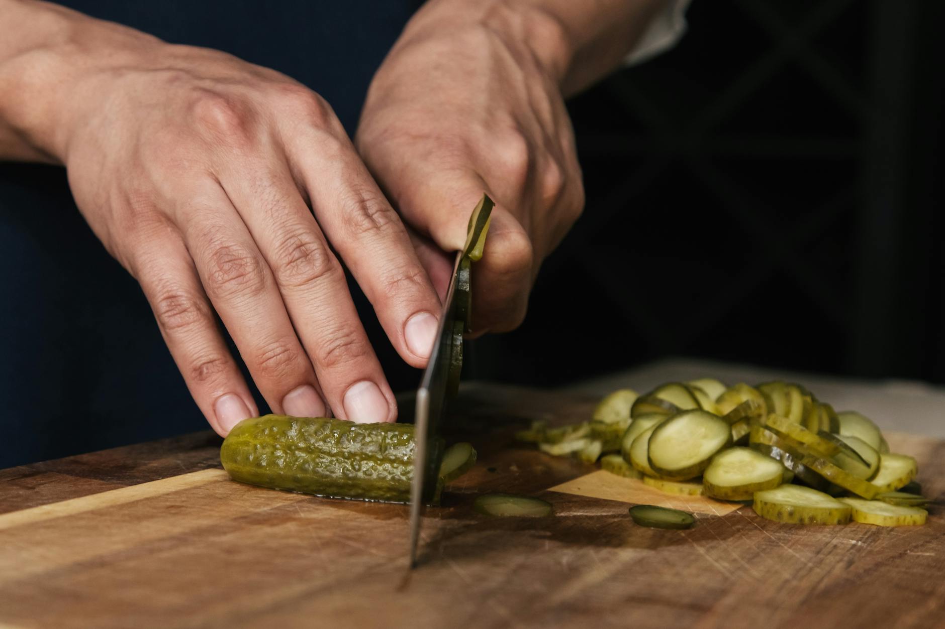 Tzatziki original griechisch – Gurken werden auf dem Brett geschnitten